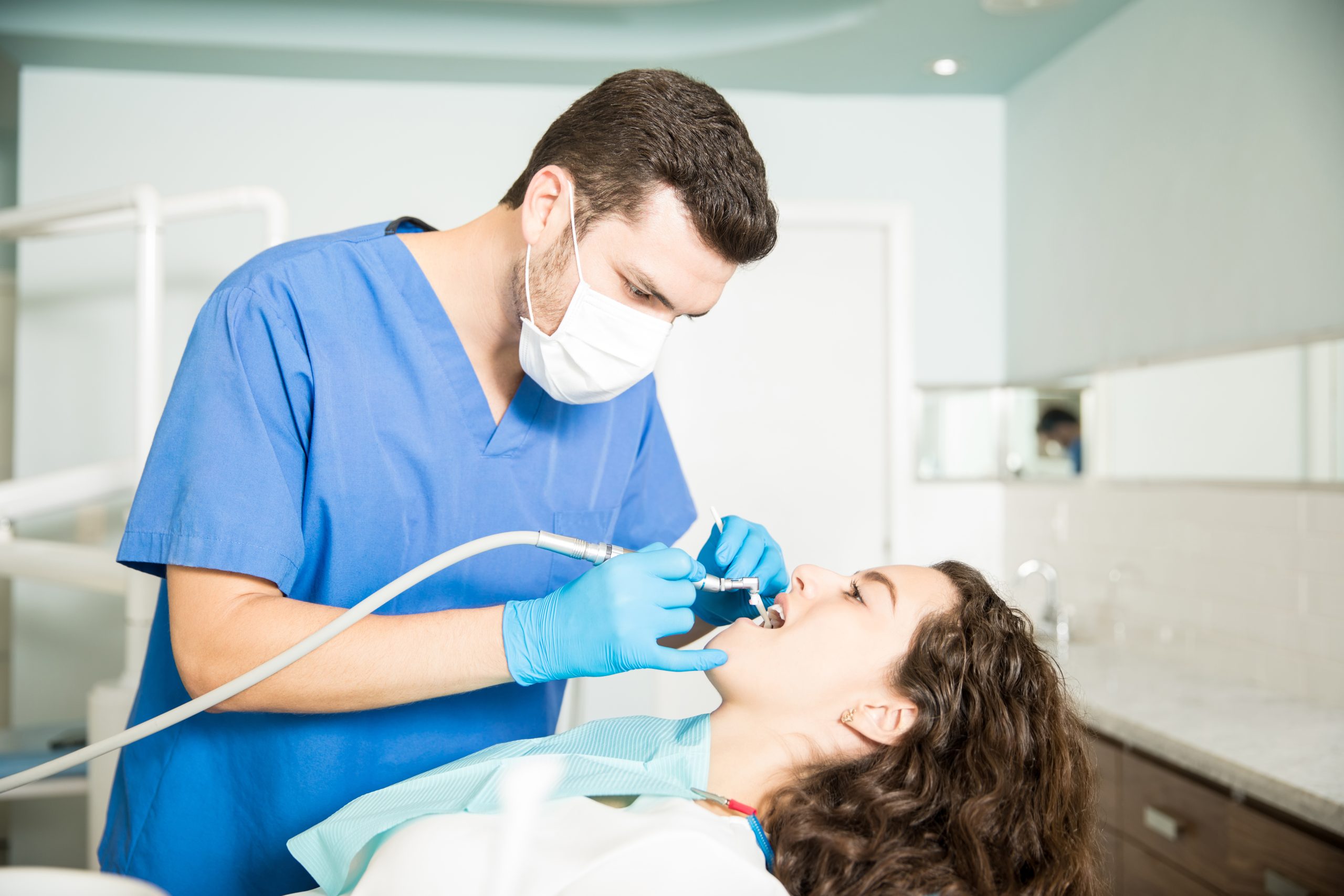 Woman Receiving Dental Treatment From Dentist In Clinic